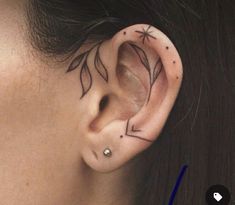 a woman's ear with an arrow tattoo on it