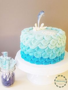 a blue and white cake sitting on top of a table next to a jar filled with candy