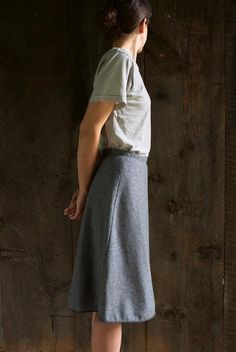 a woman standing in front of a wooden wall with her back turned to the camera