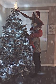 a man and woman standing in front of a christmas tree