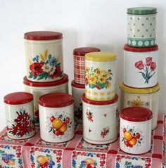 a table topped with lots of colorful canisters on top of a red and white checkered cloth