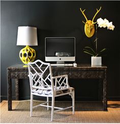 a desk with a computer, chair and lamp in front of the monitor on it