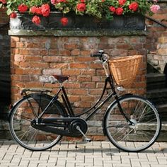 a bicycle parked next to a brick wall with flowers in the window boxes on it