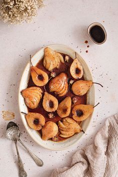 a white bowl filled with fruit next to a cup of coffee and two spoons