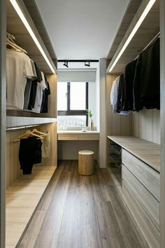 a walk in closet with wooden flooring and white walls