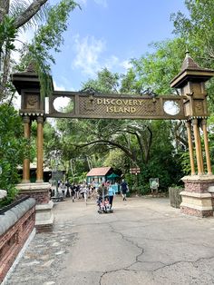 the entrance to discovery trail is surrounded by lush green trees and people walking under it