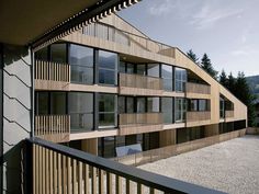 an apartment building with wooden balconies on the outside and glass windows in the front