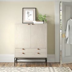 a white cabinet sitting on top of a hard wood floor next to a closet door