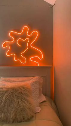 a bed with a white comforter and a neon sign above it