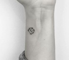 a small black and white tattoo on the wrist