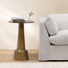 a white couch sitting next to a table with a book on it's side