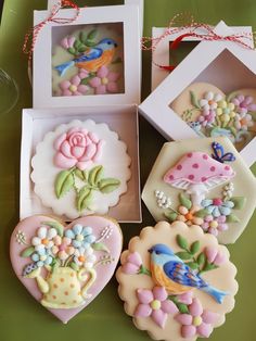 four decorated cookies in boxes on a table