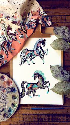 an art work with horses and leaves on the table next to it is a painting