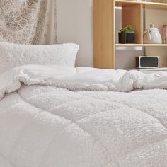 an unmade bed with white comforter and pillows on top of it in a bedroom