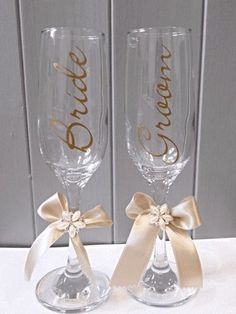 two wine glasses with bows and the word bride written on them are sitting next to each other