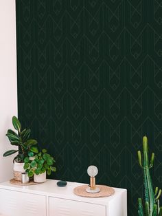 a green wall with some plants on it and a white cabinet in the corner next to it