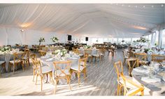 the inside of a tent with tables and chairs set up for a wedding or other function