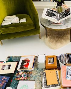 a green chair sitting next to a table filled with books and magazines on top of a white floor