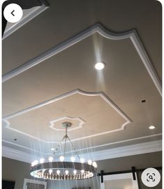 a chandelier hanging from the ceiling in a room with white walls and ceilings