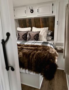 a bed sitting in the corner of a room with pillows and blankets on top of it