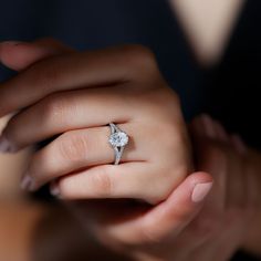 a woman's hand with a diamond ring on her left hand and the other hand holding an engagement ring