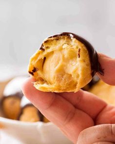 a hand holding a half eaten chocolate covered doughnut