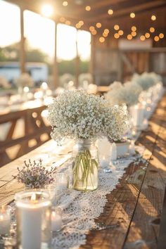 a long table with candles and vases filled with baby's breath flowers on it