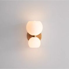 a wall light with two white balls on it's face and one is gold