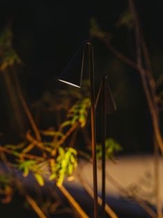 a lamp that is sitting on the ground next to some grass and trees in the background