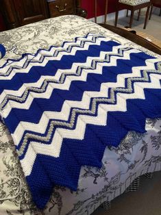 a blue and white blanket on top of a bed in a room with wooden furniture