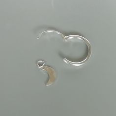 A PAIR of sterling silver hoops. Comes with a detachable and delicate crescent moon charm. The charm is multipurpose and can be used with a neck or bracelet chain too. Dimension: Hoop- 12x1.5 mm Charm- 4 x 9 mm Drop length- 18 mm Price is for ONE PAIR. These earrings are made of 925 hypoallergenic sterling silver. Most of my pieces come with a 925 stamp. Can be packaged in a gift box. I can include a personal message from you if needed You are welcome to contact me at... bhavnakwintra1956@gmail. Silver Crescent Cartilage Earrings With Moon Charm, Silver Crescent Single Cartilage Earring, Silver Moon Hoop Earrings For Pierced Ears, Minimalist Sterling Silver Hoop Earrings With Moon Charm, Silver Moon-shaped Hoop Earrings, Minimalist Silver Moon Phase Earrings, Silver Moon Charm Earrings For Everyday, Silver Cartilage Earrings With Moon Charm As Gift, Sterling Silver Crescent Cartilage Earrings With Moon Charm