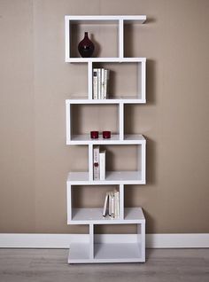 a white shelf with books and vases on it against a wall in an empty room