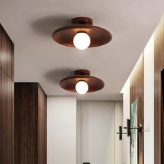 three lights are hanging from the ceiling in a hallway with wood paneling and white walls