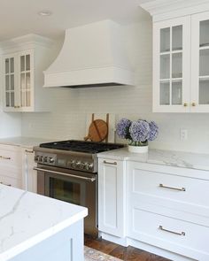 a kitchen with white cabinets and marble counter tops is pictured in this image, there are blue flowers on the stove