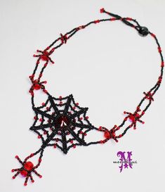 a black and red beaded necklace with spider webs hanging from it's center