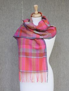 a pink and orange plaid scarf on a mannequin head stand in front of a gray background