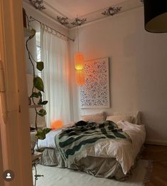 a bedroom with white walls and wooden flooring is pictured in this image, there are plants growing on the wall next to the bed