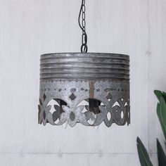 an old tin can hanging from a chain with a plant in the corner next to it