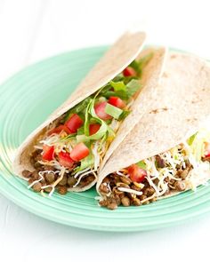 a taco on a plate with lettuce, tomatoes and other toppings