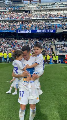 two young boys are hugging each other in front of an audience at a soccer game