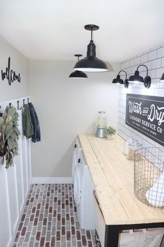 a kitchen with white cabinets and wooden counter tops, hanging lights above the sink and on the wall is a sign that says wash and dry laundry service