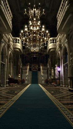 an ornate hallway with chandelier and blue carpet