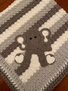 a crocheted blanket with an octopus on it sitting on a wooden floor next to a pair of scissors