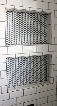 a white tiled bathroom with two shelves on the wall