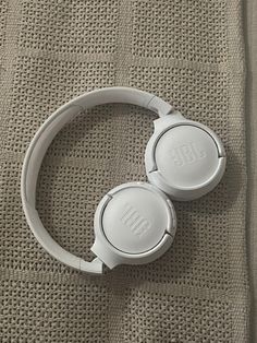 two white headphones sitting on top of a bed