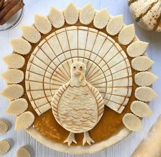 an apple pie with a turkey decoration on it and some cinnamon sticks next to it