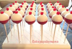 cake pops with red bows on them sitting on a white tray in front of a couch