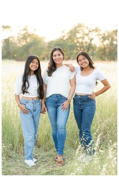 three women standing in tall grass with their arms around each other