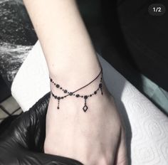 a woman's arm with a black beaded bracelet on it and a small diamond