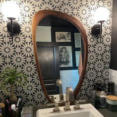 a bathroom sink sitting under a large mirror next to a wall mounted faucet